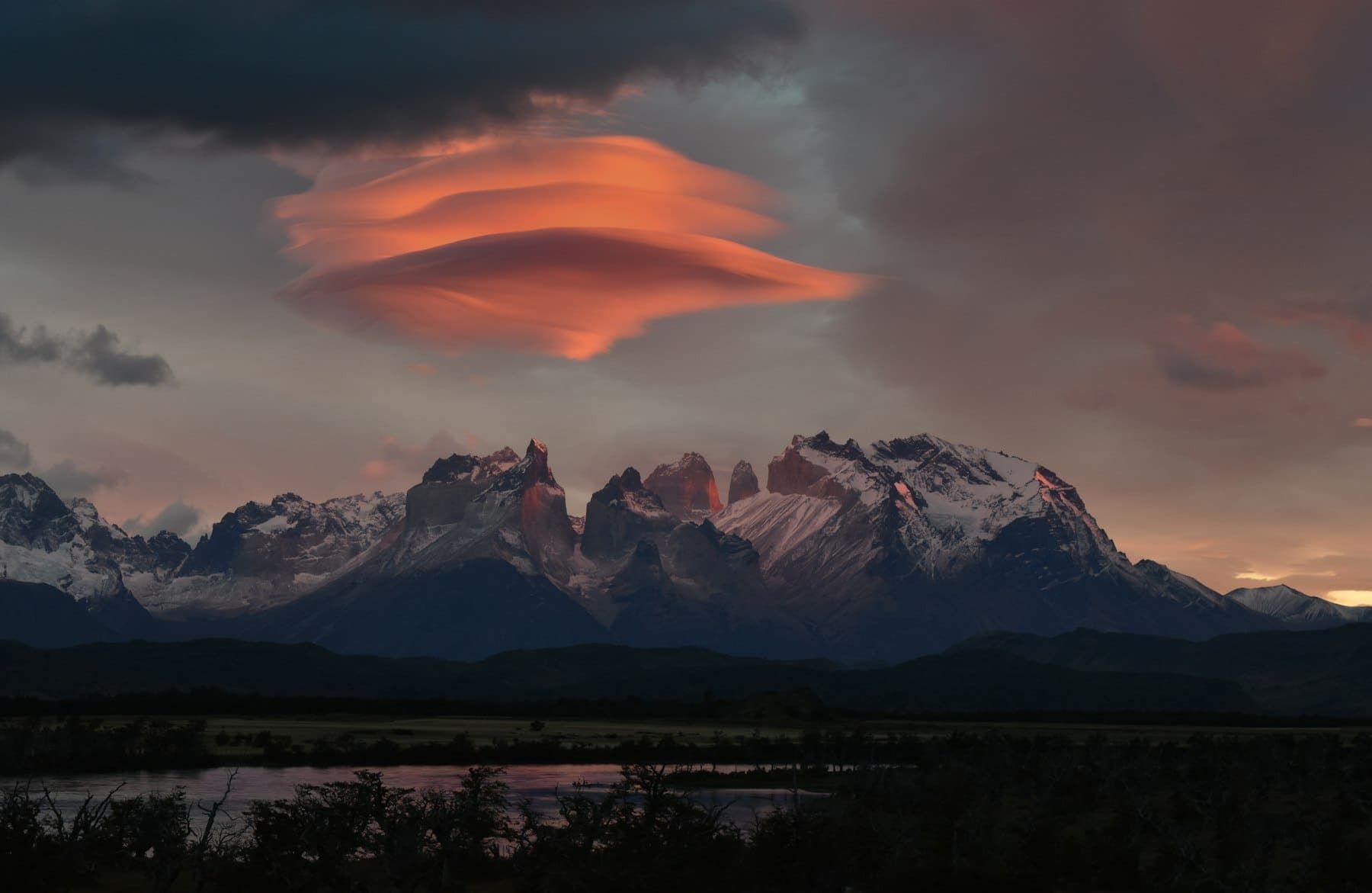Lenticular cloud glowing red over the snow-capped peaks of Torres del Paine at sunrise