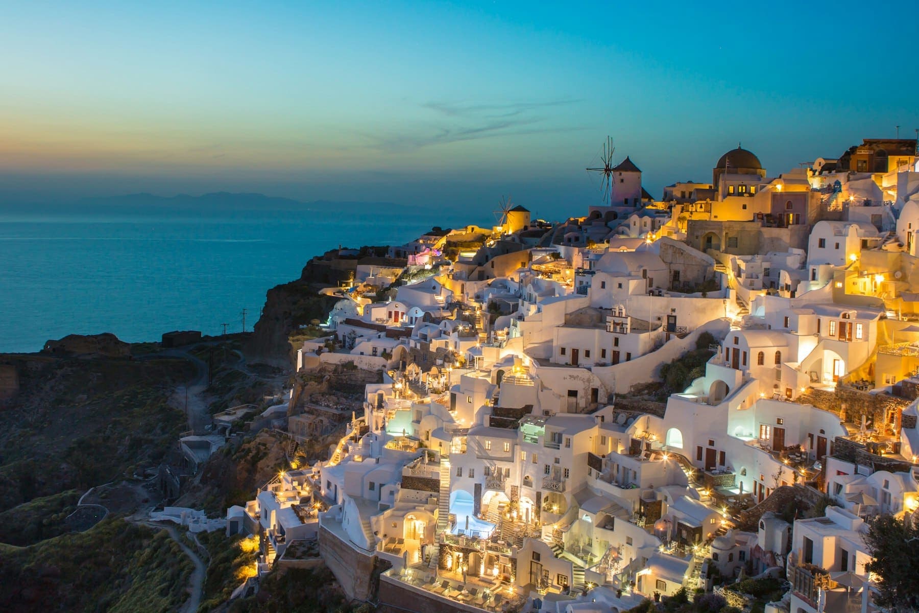 The white cliffside village of Oia, Santorini, glowing at dusk above the Aegean Sea